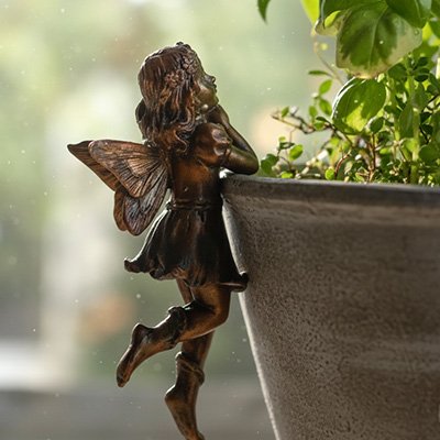 Statue de jardin féérique appuyée sur le pot
