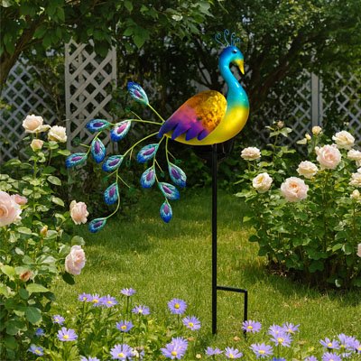Statue de jardin paon coloré près des plate-bandes de fleurs